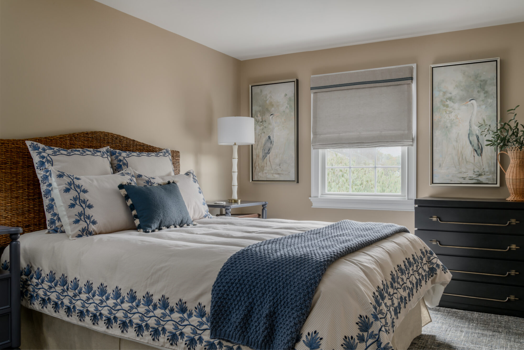 Marlton, New Jersey, guest bedroom with blue embroidered cream bedding, rattan headboard and black dresser